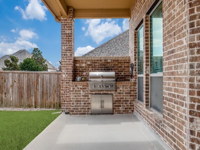 view of patio / terrace featuring an outdoor kitchen, fence, and a grill