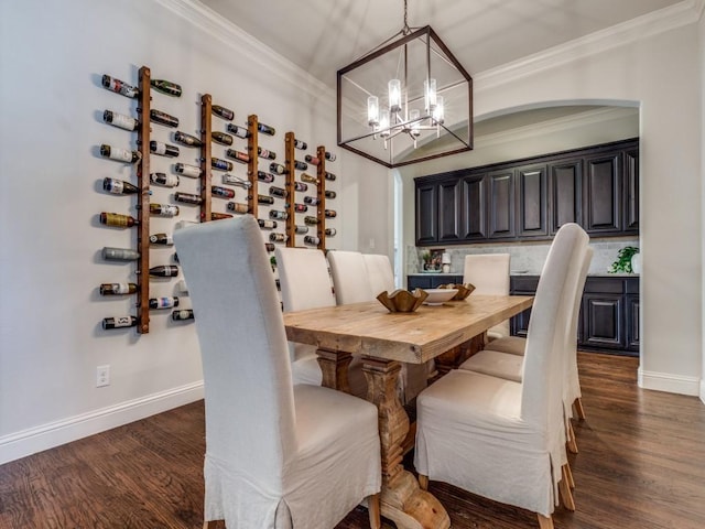 dining area with an inviting chandelier, crown molding, baseboards, and dark wood-style flooring