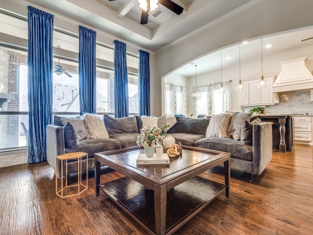 living room featuring a tray ceiling, arched walkways, crown molding, ceiling fan, and dark wood-style flooring