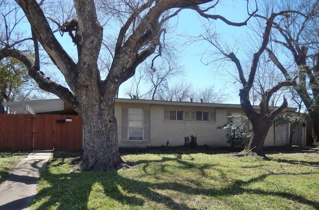 view of front of house with brick siding, a front yard, and fence