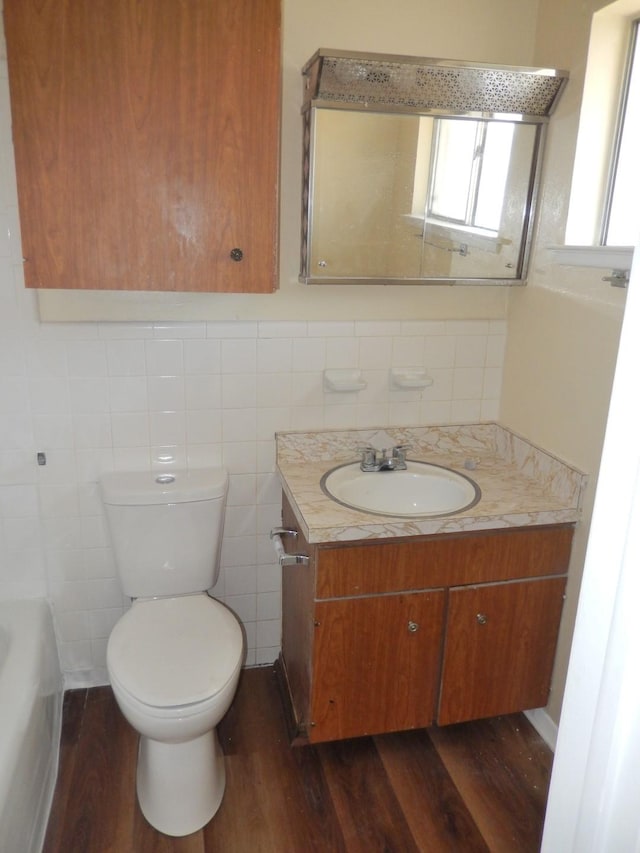 bathroom featuring a wealth of natural light, toilet, wood finished floors, and vanity