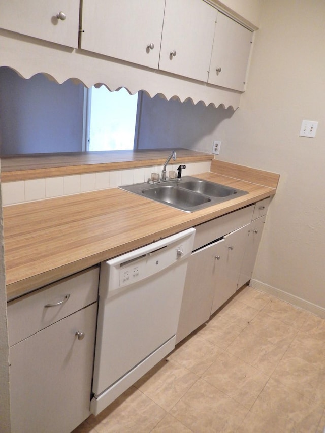 kitchen featuring baseboards, a sink, light countertops, white cabinets, and dishwasher