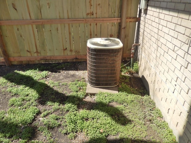 details with brick siding, central AC unit, and fence