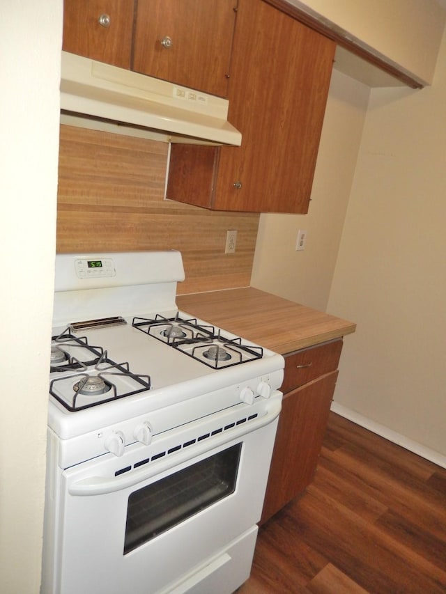 kitchen featuring under cabinet range hood, brown cabinets, white range with gas stovetop, and dark wood-style floors