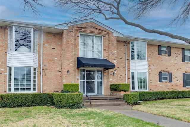 view of front of home featuring brick siding and a front yard