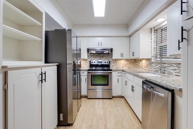 kitchen with a sink, under cabinet range hood, white cabinetry, stainless steel appliances, and light wood finished floors