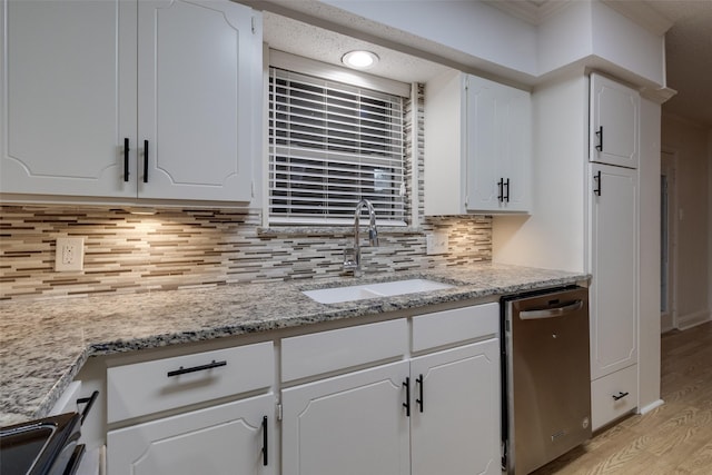 kitchen with tasteful backsplash, light wood finished floors, stainless steel dishwasher, white cabinetry, and a sink