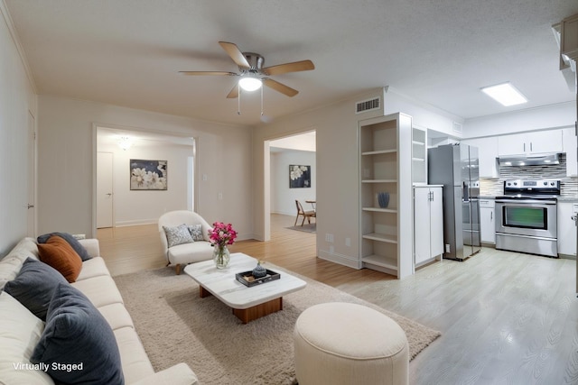 living area featuring a ceiling fan, visible vents, baseboards, light wood-style floors, and crown molding