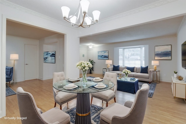 dining space with light wood-style flooring, baseboards, ornamental molding, and a chandelier