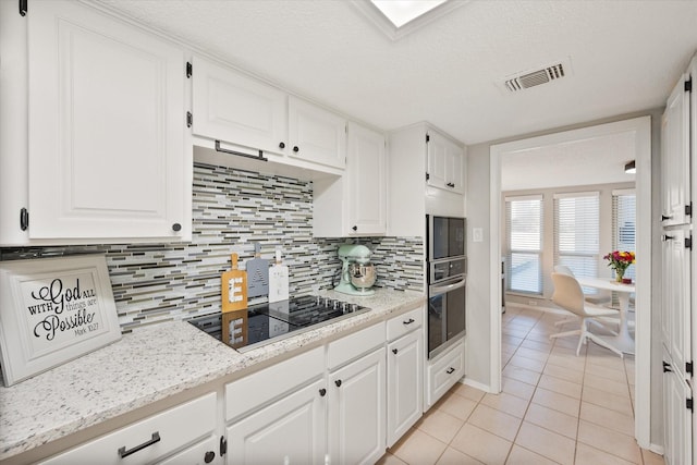 kitchen with visible vents, oven, light tile patterned floors, white cabinetry, and black electric cooktop