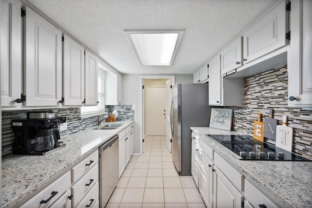 kitchen with a sink, white cabinetry, appliances with stainless steel finishes, light tile patterned floors, and decorative backsplash