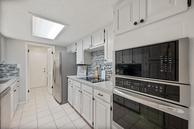 kitchen featuring light tile patterned floors, stainless steel appliances, tasteful backsplash, and white cabinets