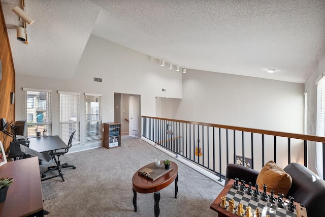 carpeted office with visible vents, a textured ceiling, and high vaulted ceiling