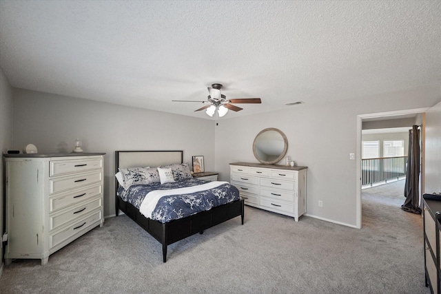 bedroom featuring visible vents, baseboards, light carpet, a textured ceiling, and a ceiling fan