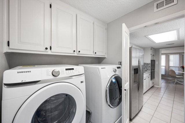 laundry room featuring visible vents, light tile patterned flooring, cabinet space, a textured ceiling, and independent washer and dryer