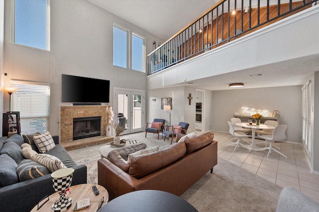 living room with visible vents, a high ceiling, tile patterned flooring, baseboards, and a tile fireplace