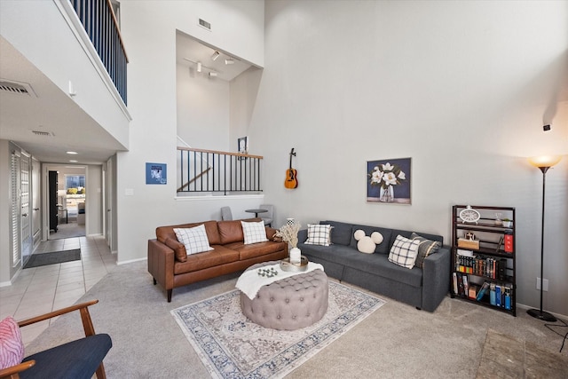 carpeted living room with baseboards, visible vents, and a towering ceiling