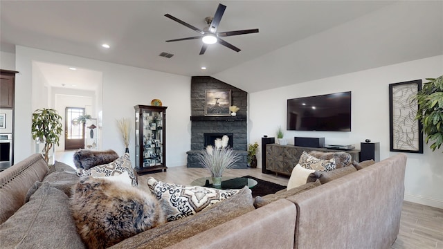 living room with a ceiling fan, visible vents, a fireplace, vaulted ceiling, and light wood-style floors