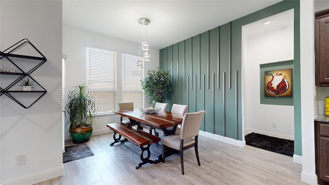 dining space with baseboards and light wood-style floors