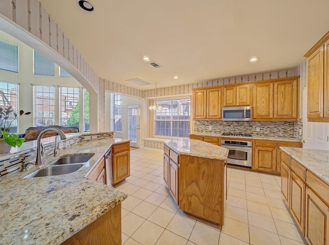 kitchen featuring light tile patterned flooring, appliances with stainless steel finishes, a center island, and a sink