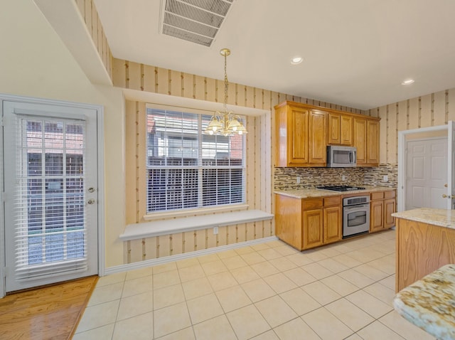 kitchen featuring visible vents, stainless steel appliances, an inviting chandelier, wallpapered walls, and light tile patterned floors