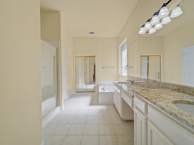 full bathroom featuring tile patterned flooring, visible vents, double vanity, a bath, and a sink