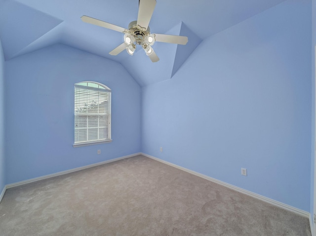 empty room featuring vaulted ceiling, carpet flooring, a ceiling fan, and baseboards