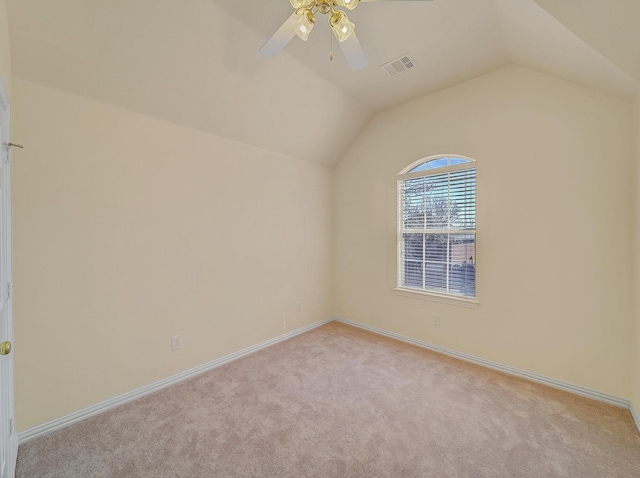 empty room with visible vents, lofted ceiling, a ceiling fan, and carpet flooring