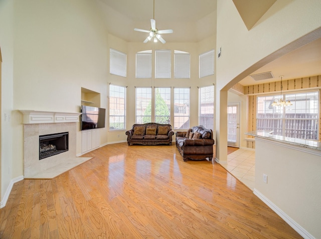 unfurnished living room with a premium fireplace, arched walkways, baseboards, and wood finished floors