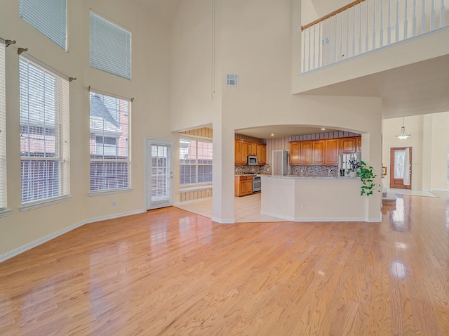 unfurnished living room featuring visible vents, baseboards, and light wood finished floors