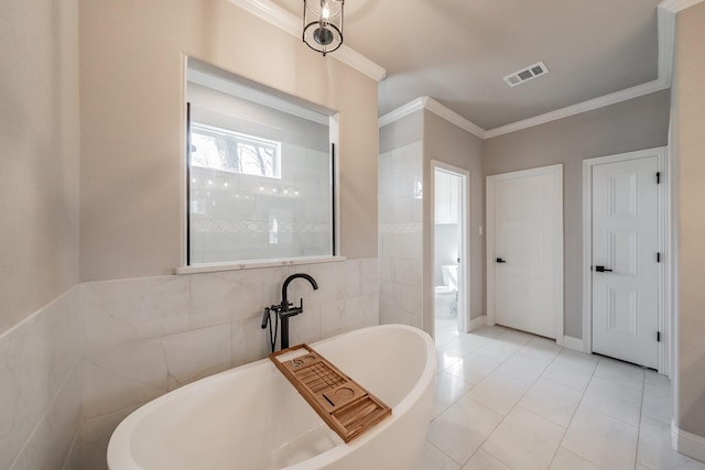 full bath featuring visible vents, a freestanding bath, ornamental molding, tile walls, and toilet