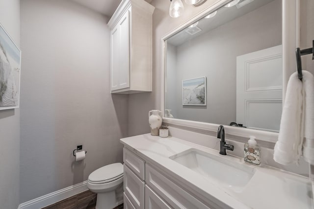 half bath featuring visible vents, toilet, wood finished floors, baseboards, and vanity