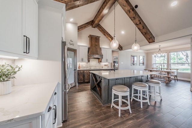 kitchen with tasteful backsplash, a spacious island, beamed ceiling, a breakfast bar area, and custom range hood