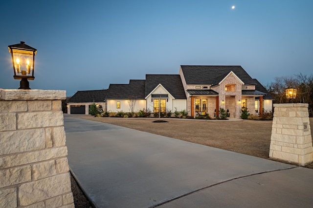 view of front of home featuring brick siding, a garage, metal roof, and a standing seam roof