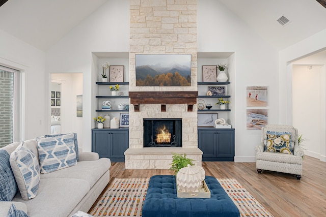 living area with visible vents, built in shelves, wood finished floors, and a fireplace