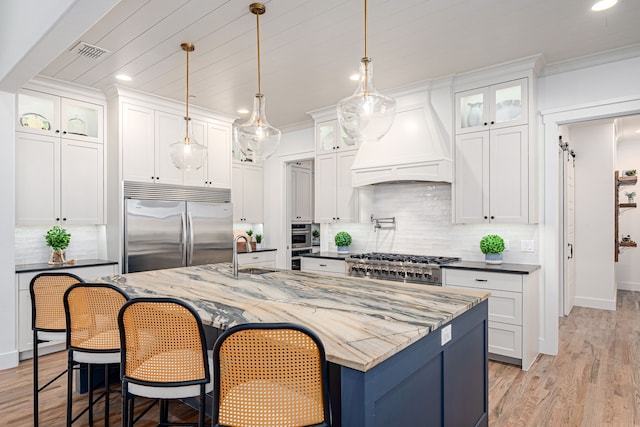 kitchen featuring visible vents, a sink, white cabinetry, appliances with stainless steel finishes, and custom exhaust hood