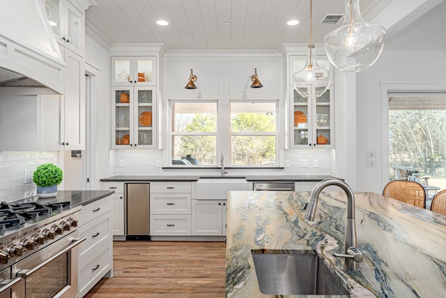 kitchen featuring visible vents, a sink, custom range hood, appliances with stainless steel finishes, and white cabinetry