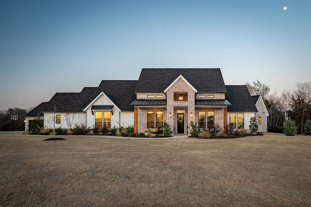 modern inspired farmhouse featuring a standing seam roof, brick siding, a front lawn, board and batten siding, and metal roof