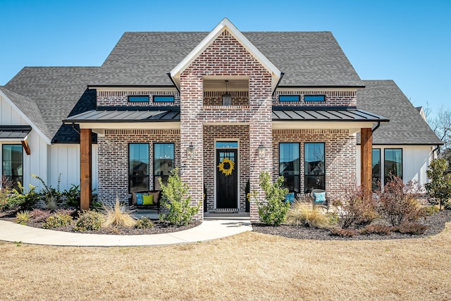 view of front of house with brick siding, board and batten siding, roof with shingles, a balcony, and a standing seam roof