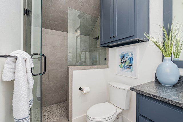 bathroom with toilet, tiled shower, and vanity