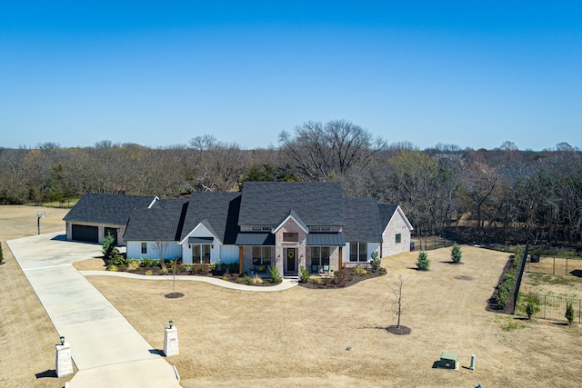 modern farmhouse with board and batten siding, fence, concrete driveway, metal roof, and a standing seam roof