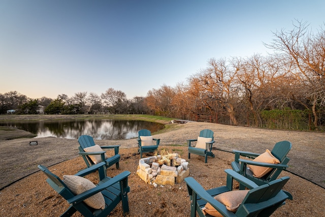 yard at dusk with a water view and an outdoor fire pit