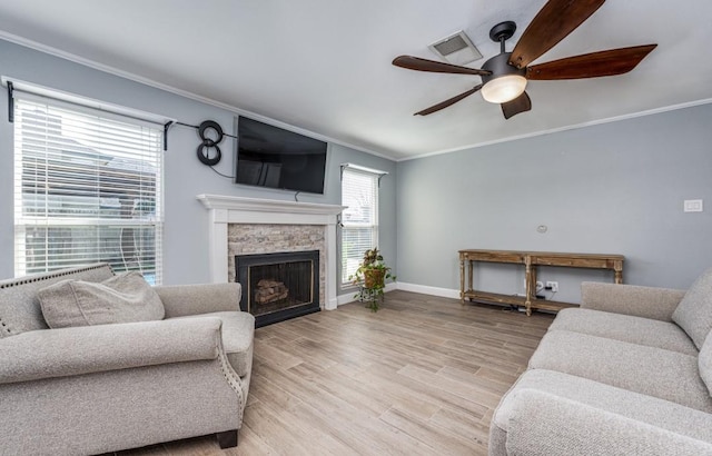 living room featuring light wood finished floors, visible vents, baseboards, ceiling fan, and ornamental molding