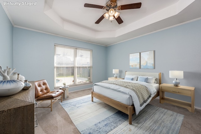 carpeted bedroom featuring ceiling fan, crown molding, a raised ceiling, and baseboards