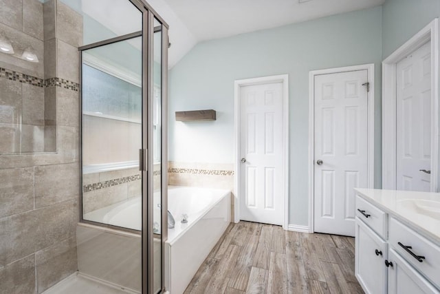 bathroom featuring a shower stall, vanity, a garden tub, and wood finished floors