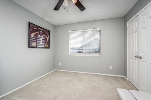 unfurnished bedroom with a closet, baseboards, light colored carpet, and ceiling fan