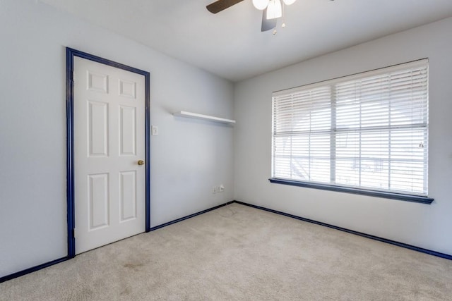 carpeted empty room featuring a ceiling fan