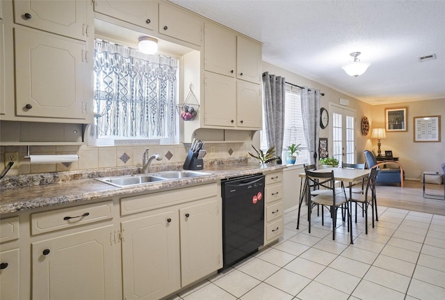 kitchen featuring visible vents, a sink, black dishwasher, light tile patterned floors, and decorative backsplash