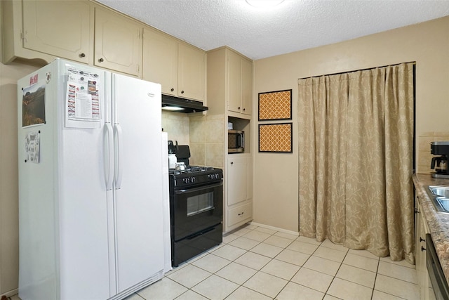 kitchen with under cabinet range hood, cream cabinets, black gas stove, freestanding refrigerator, and light tile patterned floors