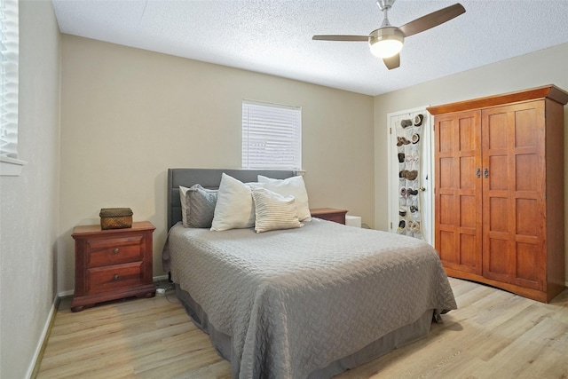 bedroom with baseboards, a textured ceiling, light wood-type flooring, and a ceiling fan